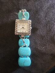 Swap brand quartz watch With distinctive square face and turquoise beaded band.